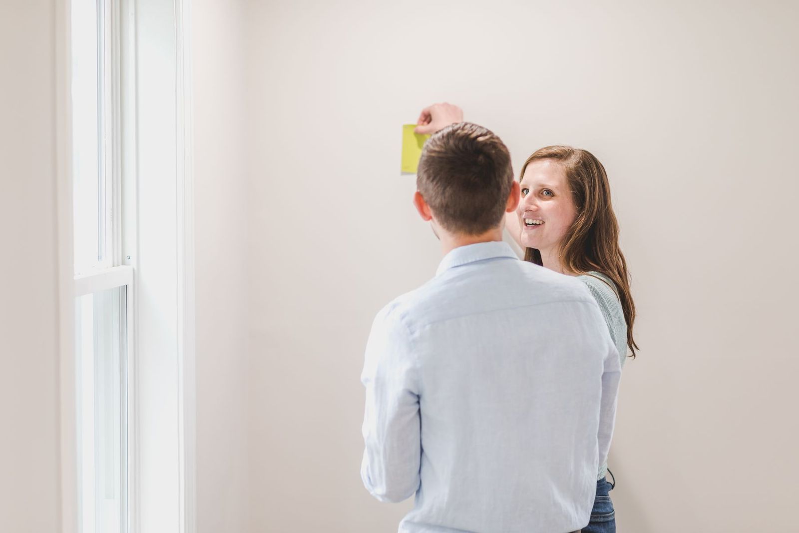 Paar hält Farbmuster an die Wand und wählt den Farbton